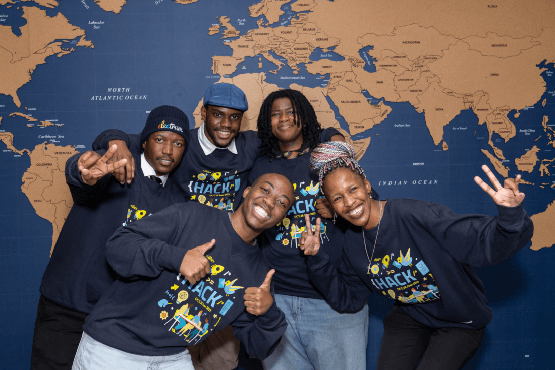 Members of Team Guava Script posing in front of a wall mural featuring a painted Earth globe.